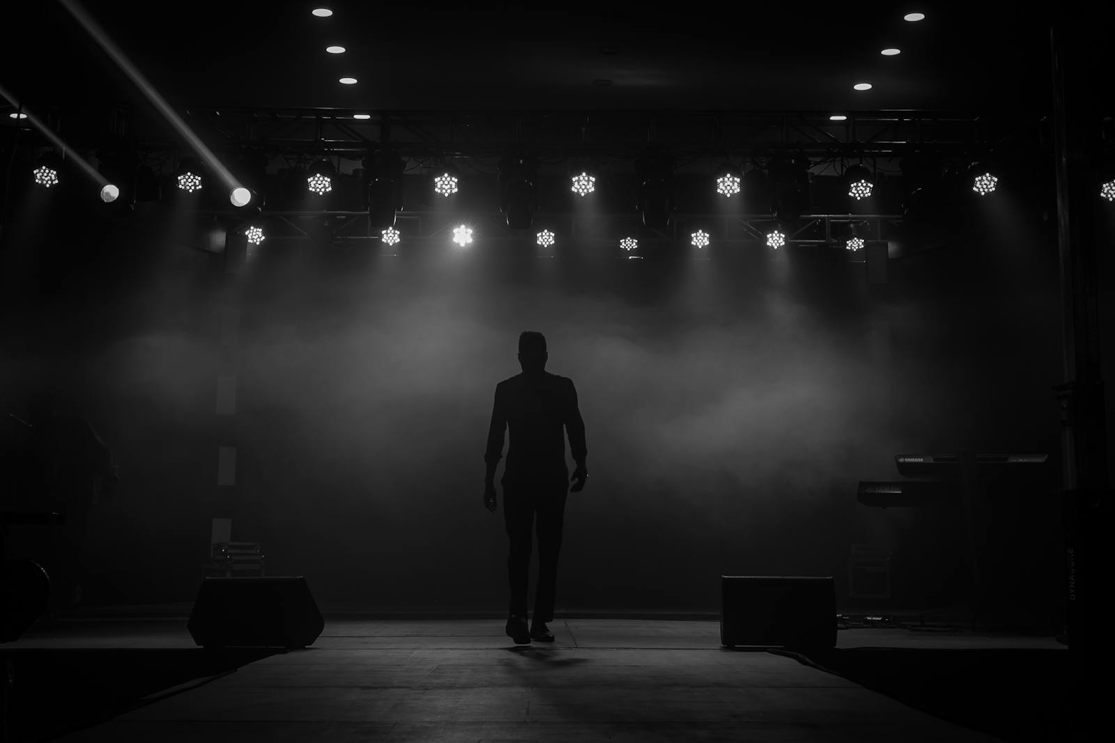 A silhouette of a performer on a stage with bright overhead lights and dramatic smoke effect in Ibadan, Nigeria.