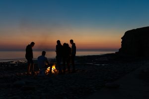 silhouette photography of people gathered around a bonfire by the beach