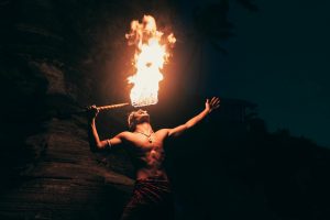 A dynamic fire eater performs at night, showcasing traditional art and skill in a dramatic setting.