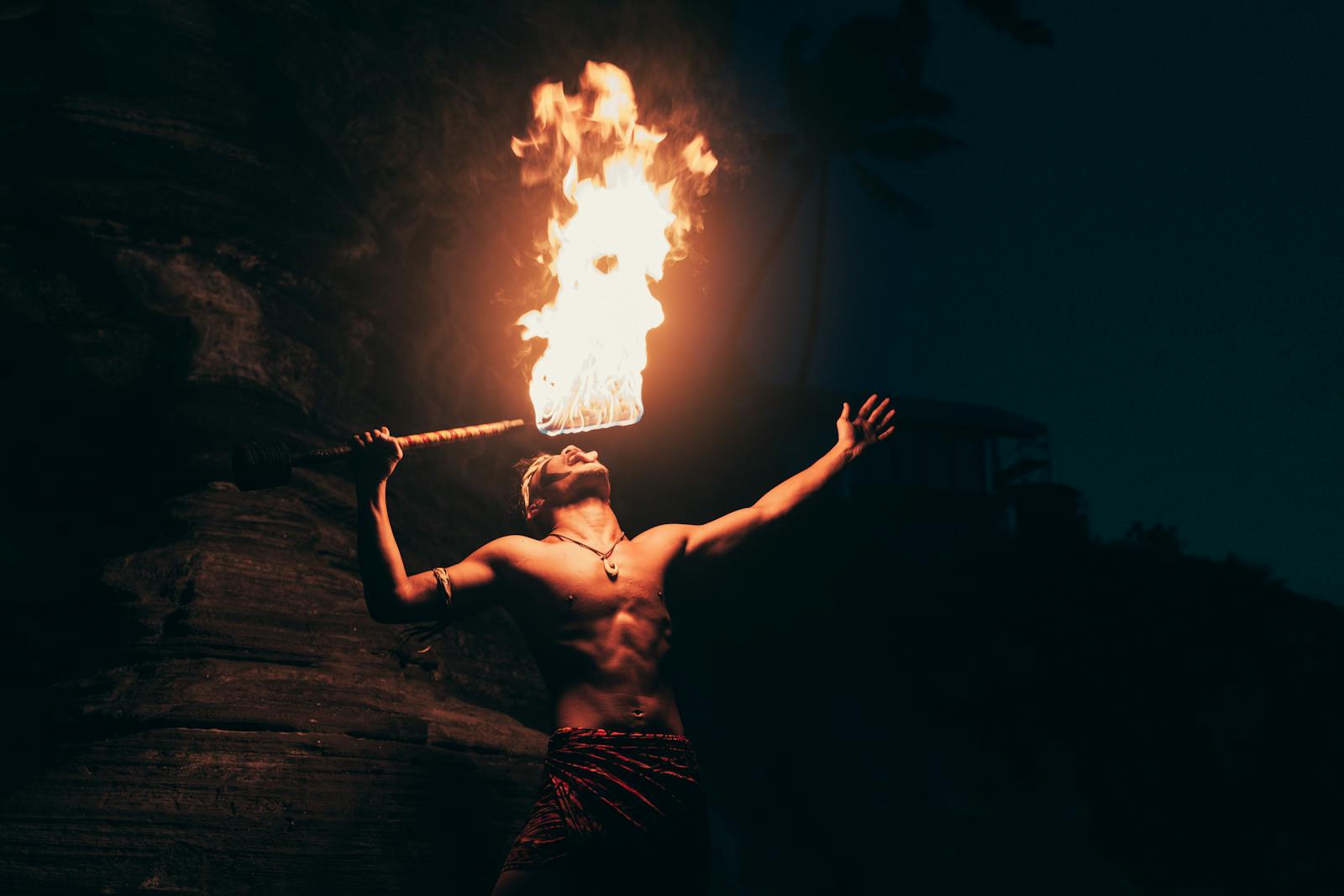 A dynamic fire eater performs at night, showcasing traditional art and skill in a dramatic setting.