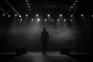 A silhouette of a performer on a stage with bright overhead lights and dramatic smoke effect in Ibadan, Nigeria.