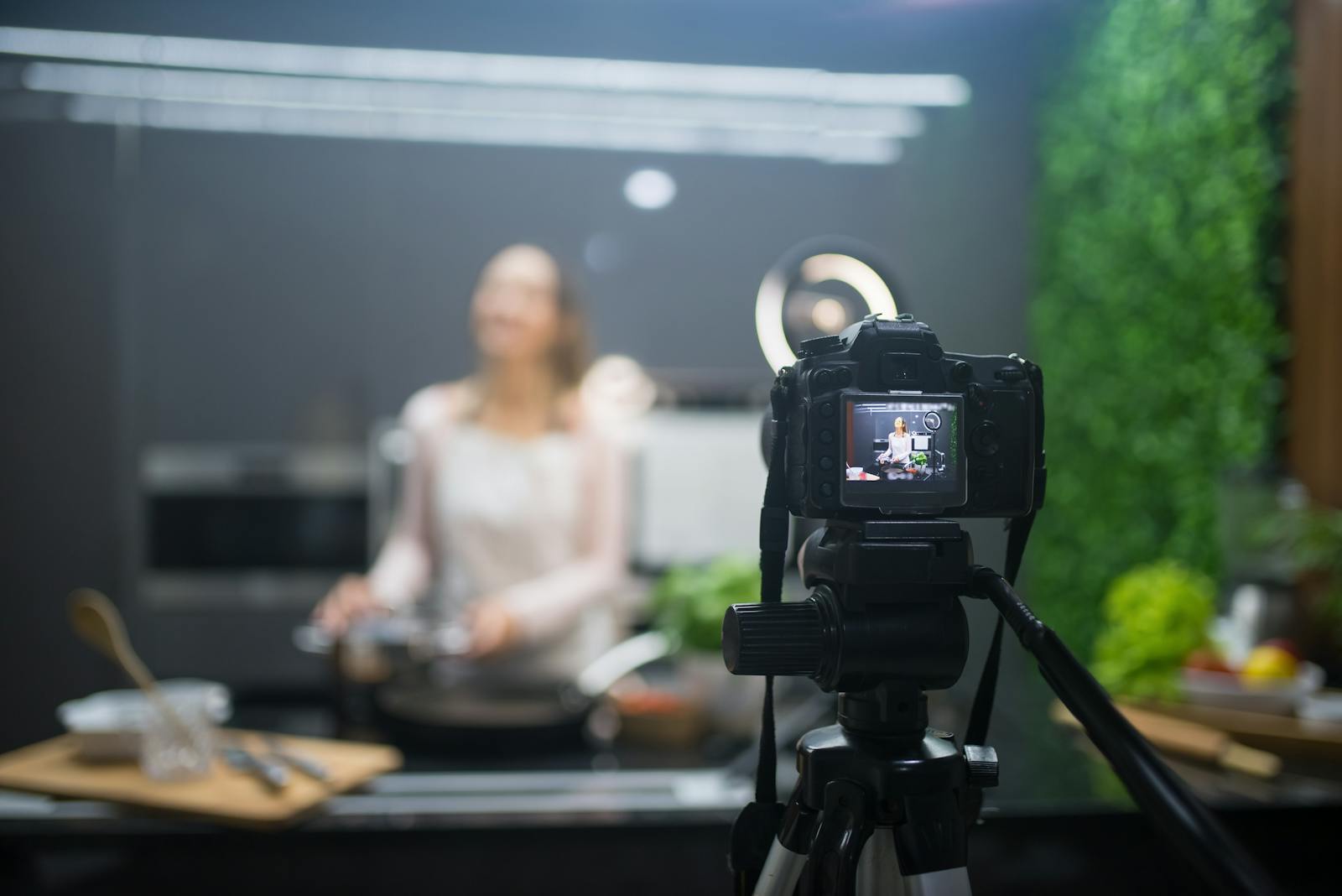 Behind the scenes of a cooking show setup with camera and tripod capturing the chef.